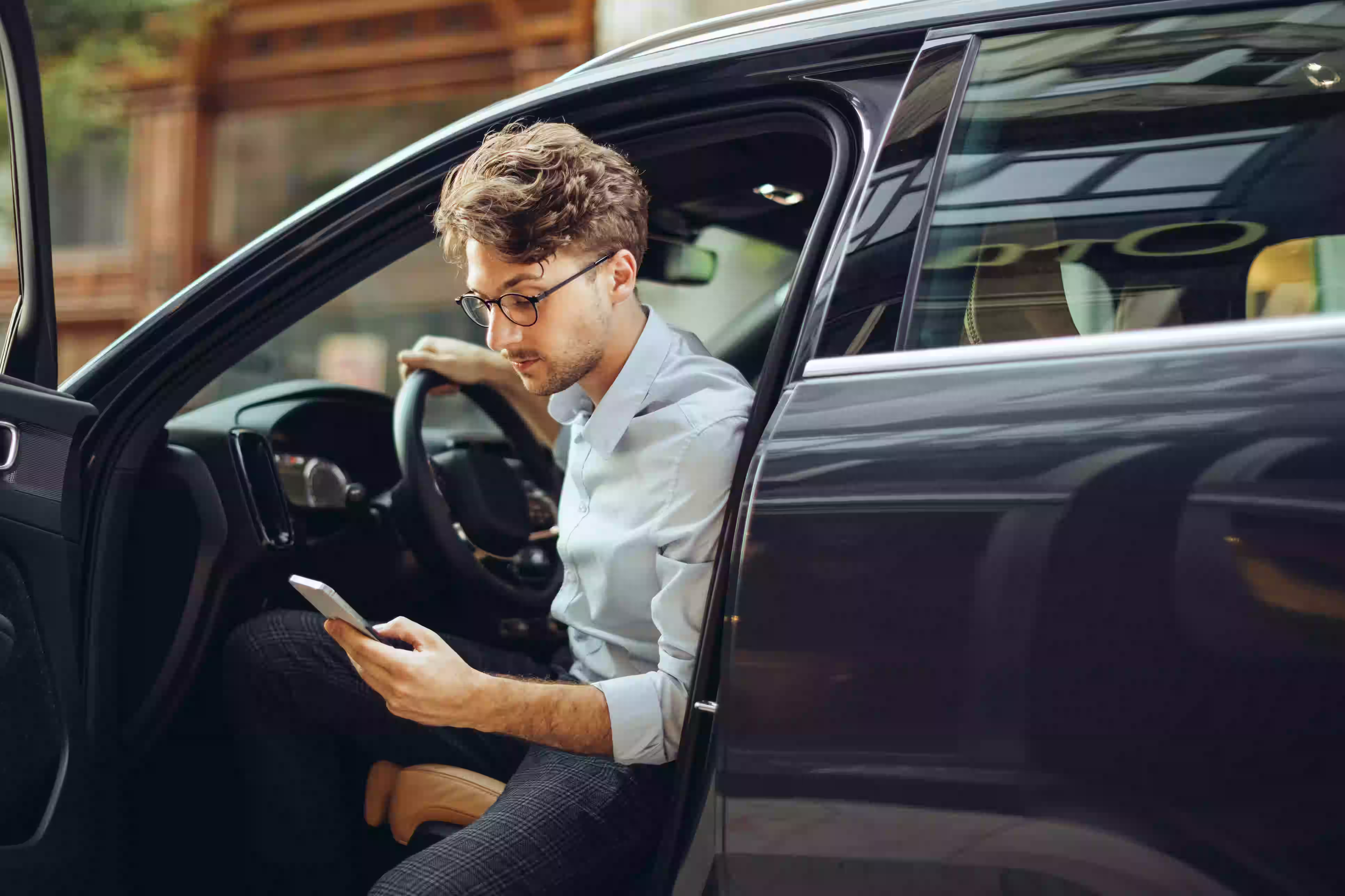 Mann nutzt Smartphone im Auto.