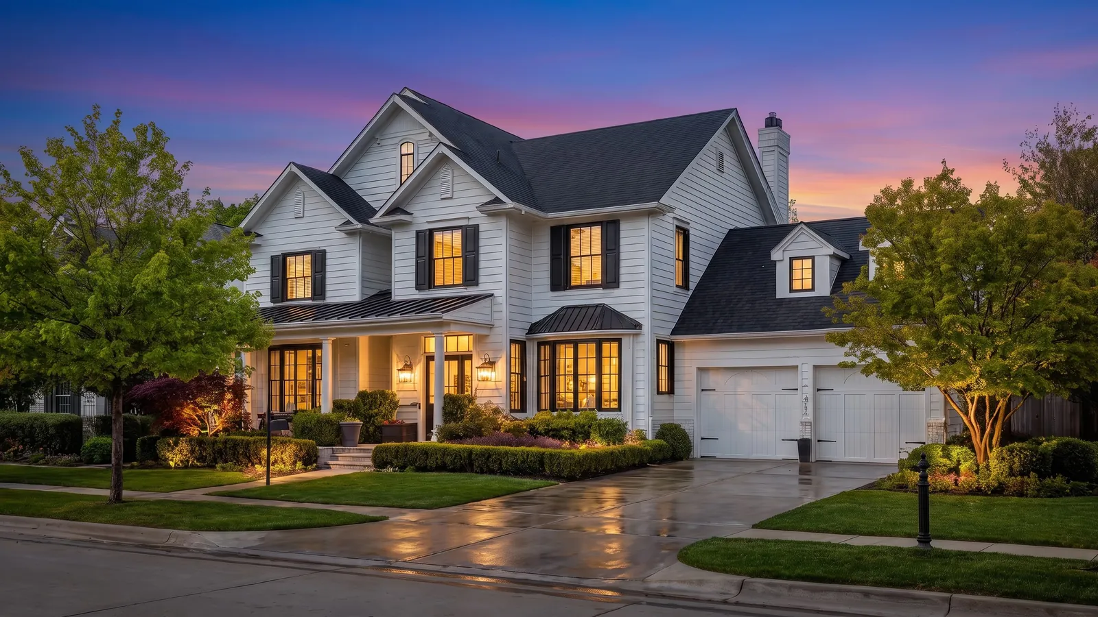 The same house at twilight with a pink and blue sky and warm lit windows
