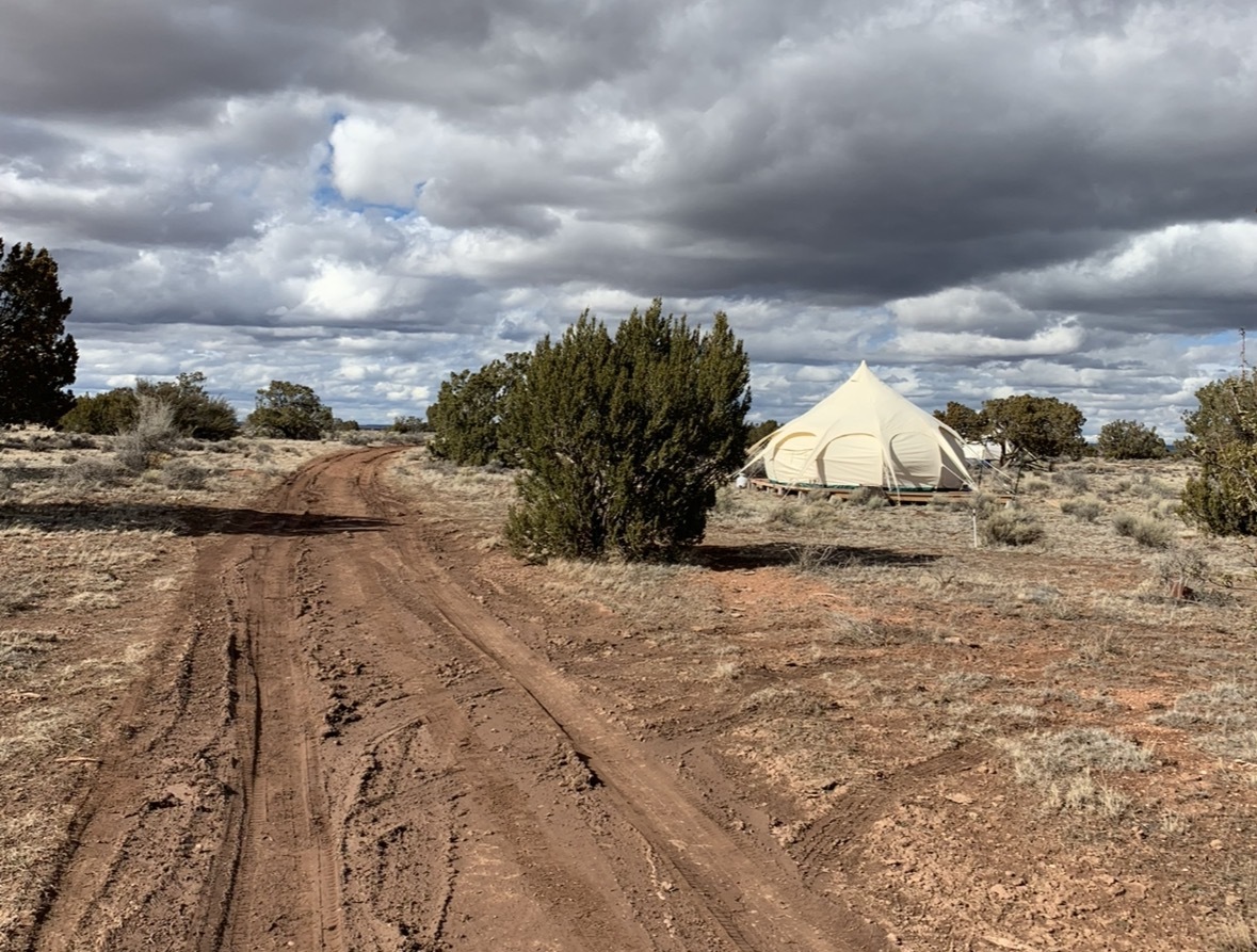 Muddy dirt road leading to a glamping tent on raw land