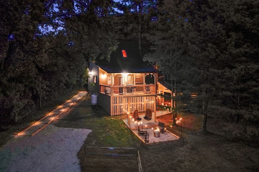 Immersive Escapes cabin at night with string lights and fire pit