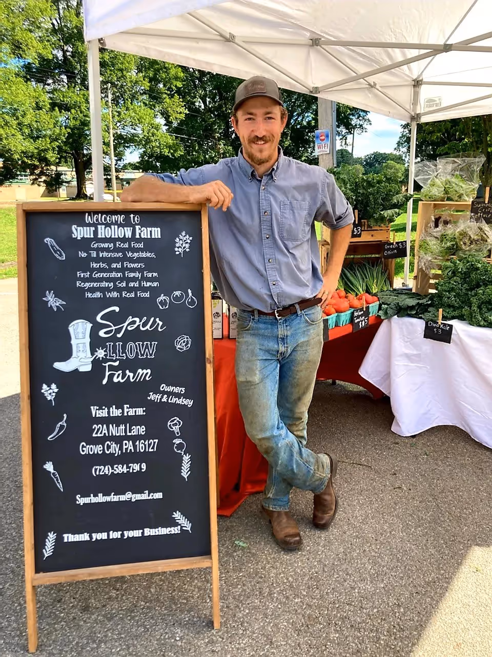 Jeff Spur Hollow Farm standing in front of booth at farmers market 