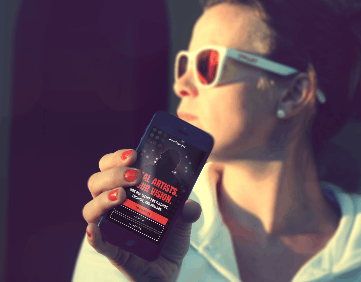 Person wearing white sunglasses holding a phone displaying mobile hero section.