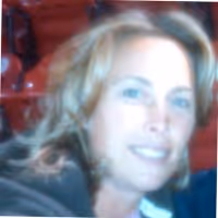 Blurred portrait of a woman with light hair smiling in front of red seats.