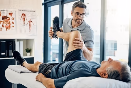 Allied health professional providing physical therapy in a clinic setting. Illustrates a healthcare journey supported by Medicity digital tools for remote patient monitoring.