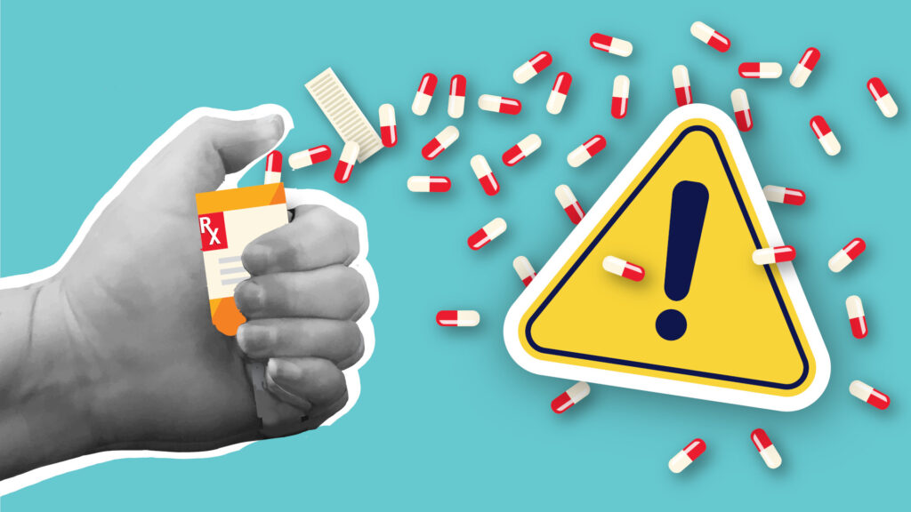 light blue background with a hand in black and white sepia, holding a yellow and orange pill bottle, the pills are spilling out with a yellow caution sign on top of them