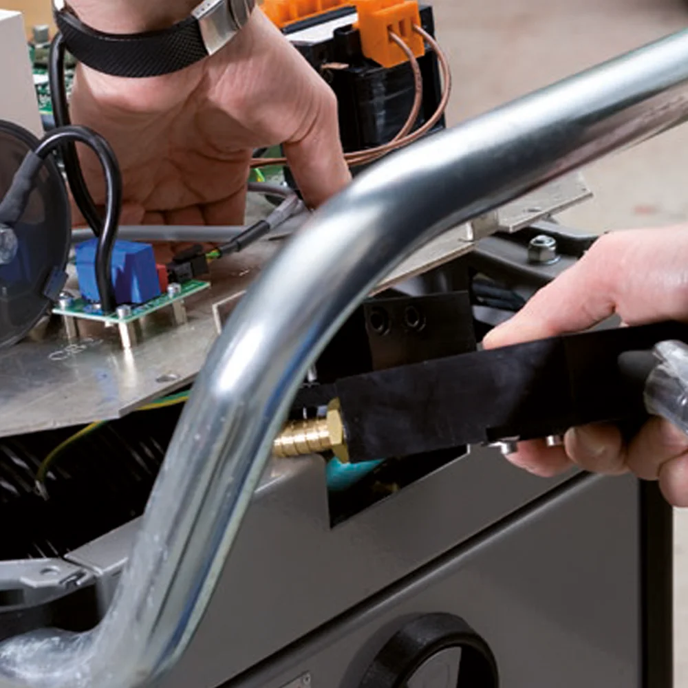 Hands repairing or assembling electronic components inside a machine with metal and circuit board parts.