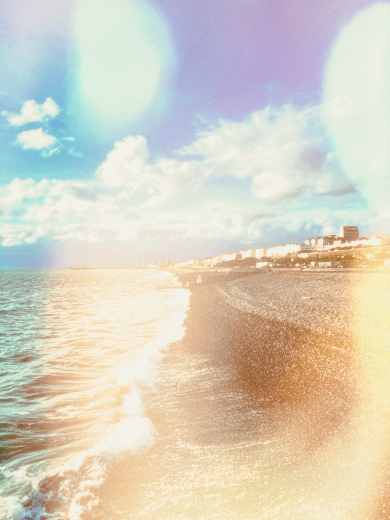 A beach and sea overlaid with soft blue and gold flare orbs