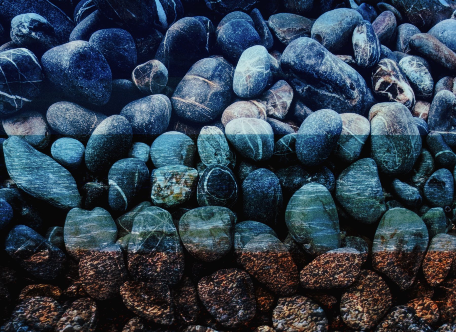A bed of pebbles washed in cool blue with warmer tones at the base