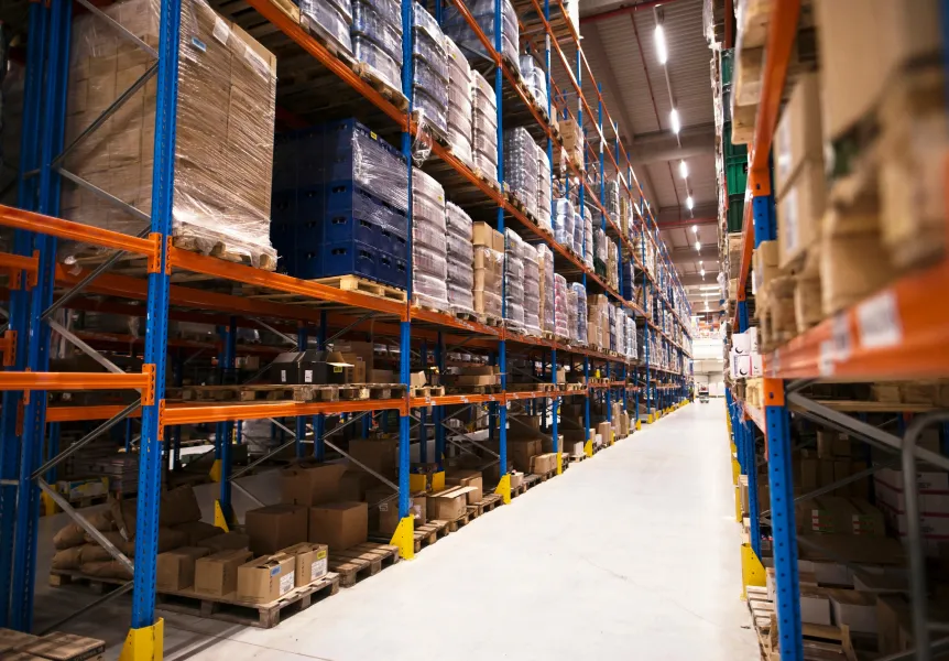 Long aisles of industrial shelving stacked with various packaged goods in a warehouse.