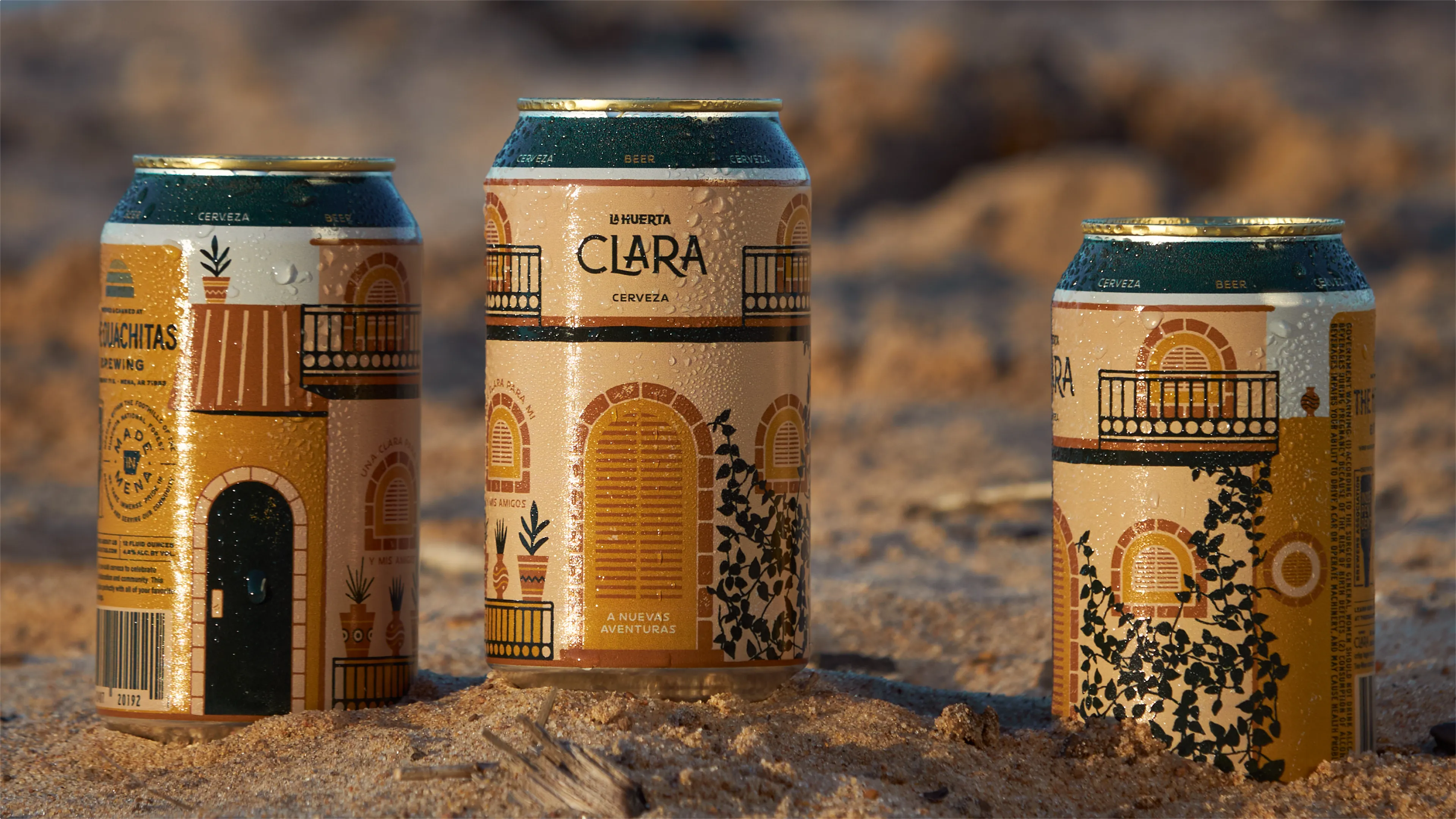 he Ouachitas La Huerta Clara cerveza beer cans with illustrated Spanish courtyard architecture design resting in sand, can design by Unbound Collective