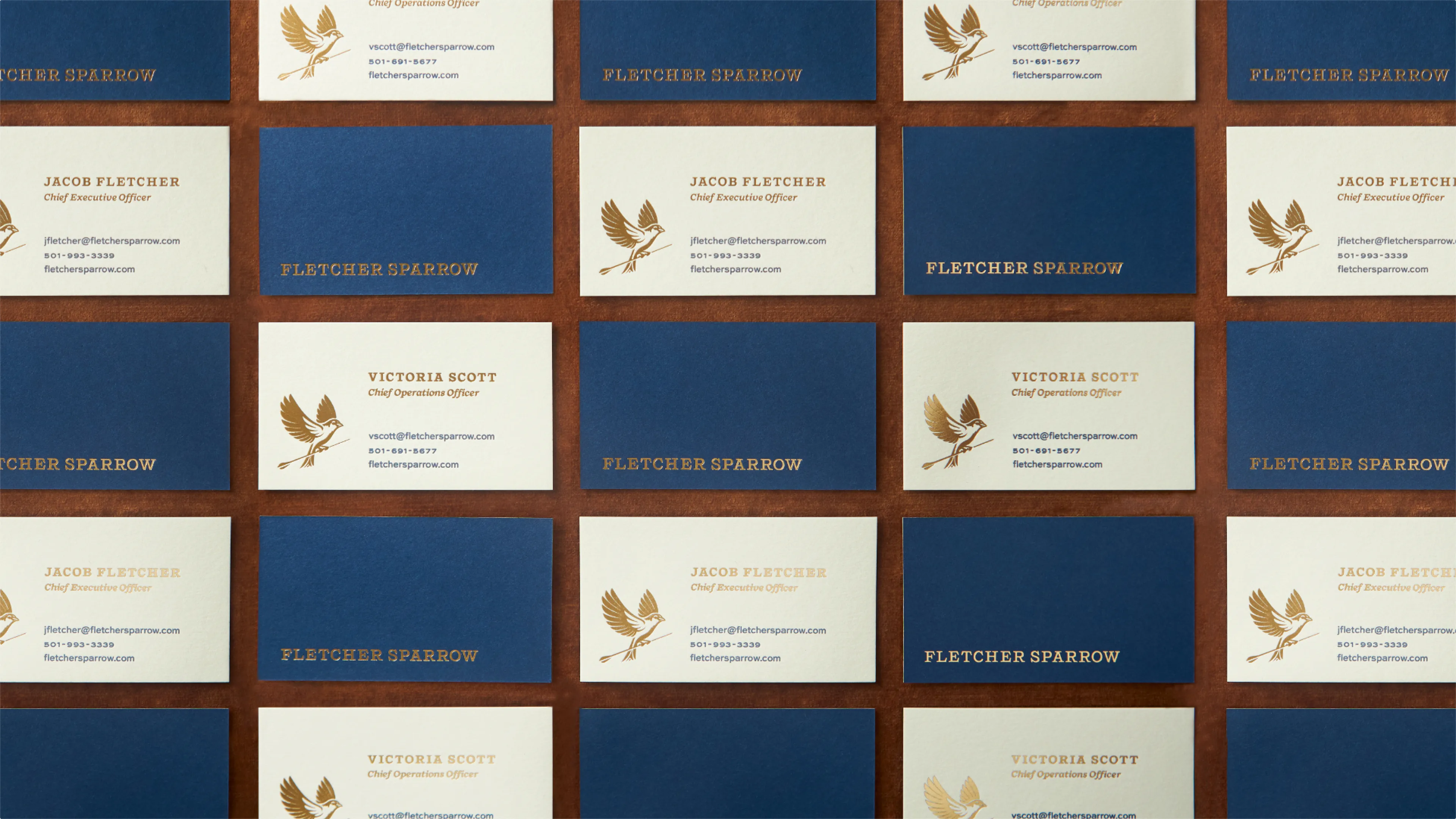 Fletcher Sparrow navy and cream business card grid on leather surface featuring gold foil sparrow illustrations for CEO Jacob Fletcher and COO Victoria Scott, designed by Unbound Collective