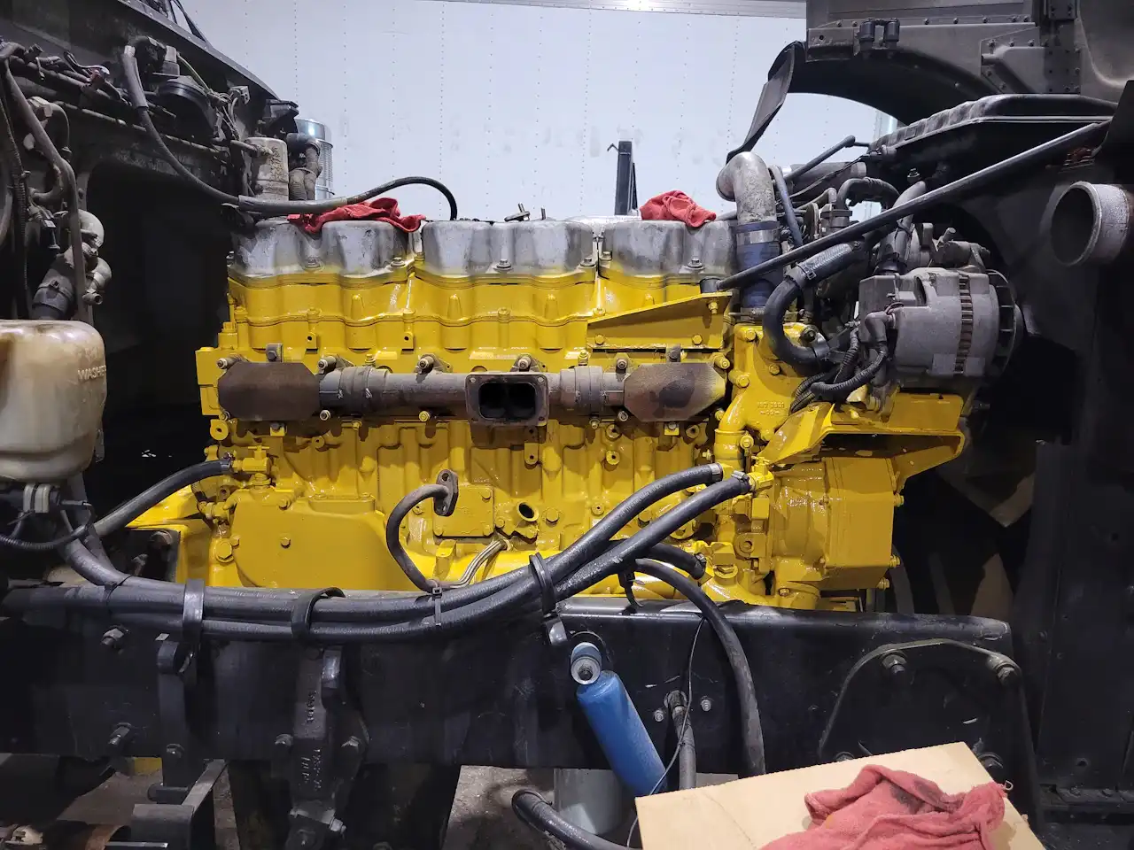 Engine repair service for a heavy-duty truck, showing a rebuilt yellow diesel engine with exposed hoses and components.