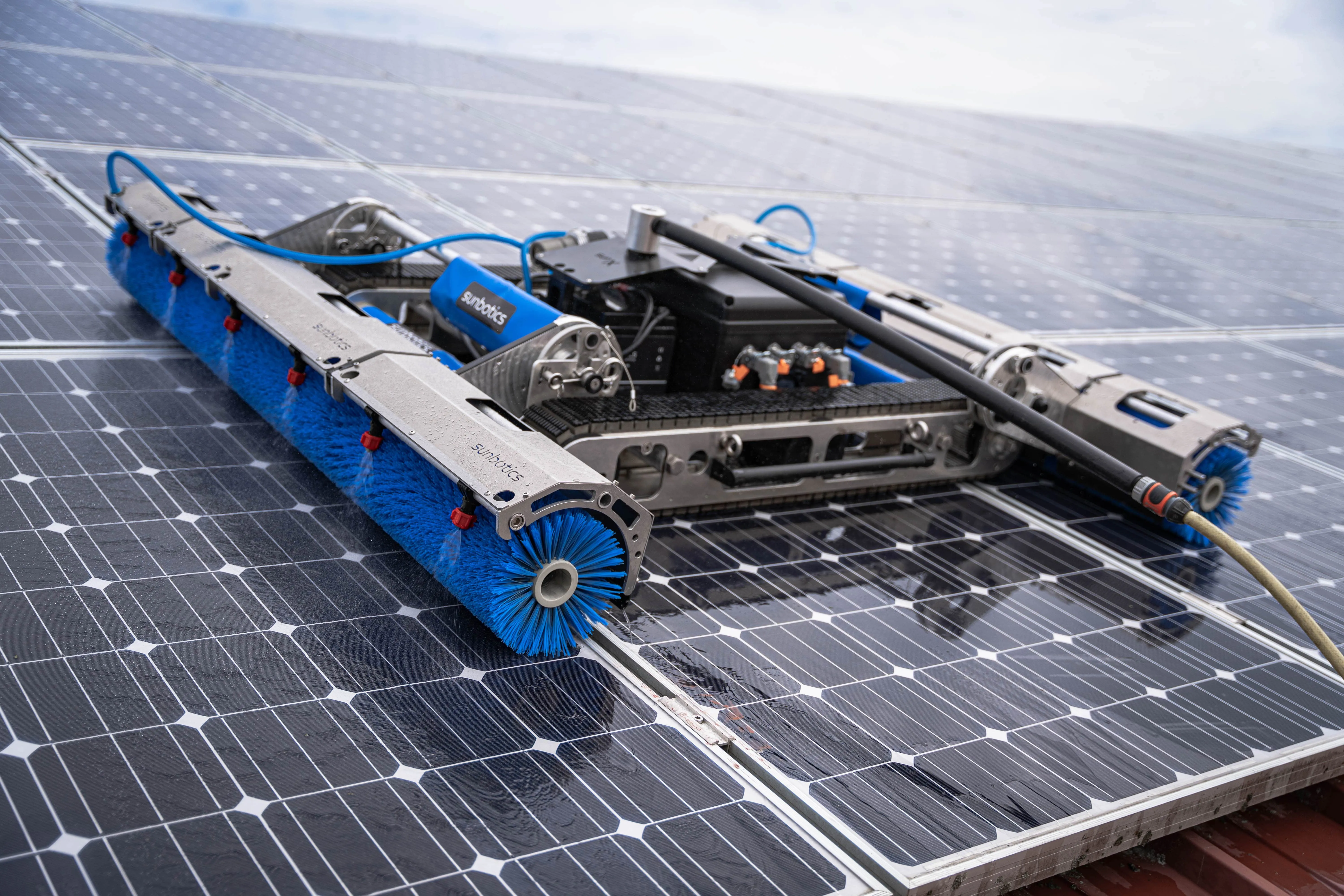 Solarroboter sun-X von Sunbotics mit blauen Bürsten im Einsatz auf einer grossen Solarpanelfläche.