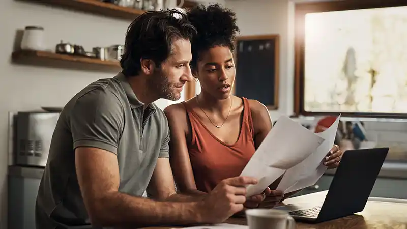 Man and woman sitting at a table comparing two documents