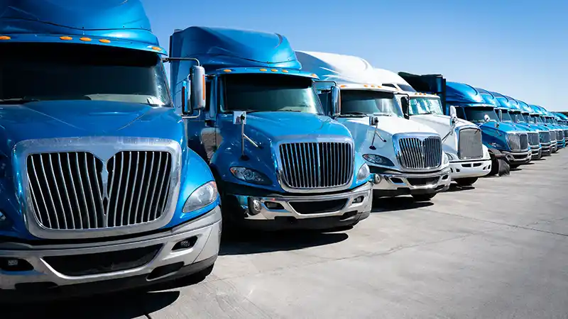 Row of blue and white semi trucks parked next to one another viewing from the front