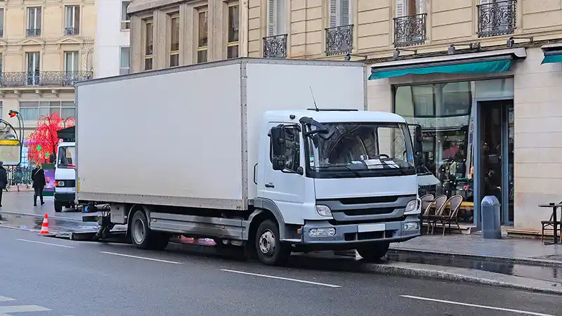 Commercial delivery truck parked on street running while unloading