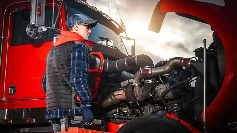 Man inspecting semi truck engine.