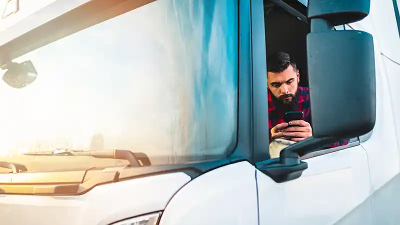 Owner-operator filling out FMCSA authority application on a mobile device in a truck cab.