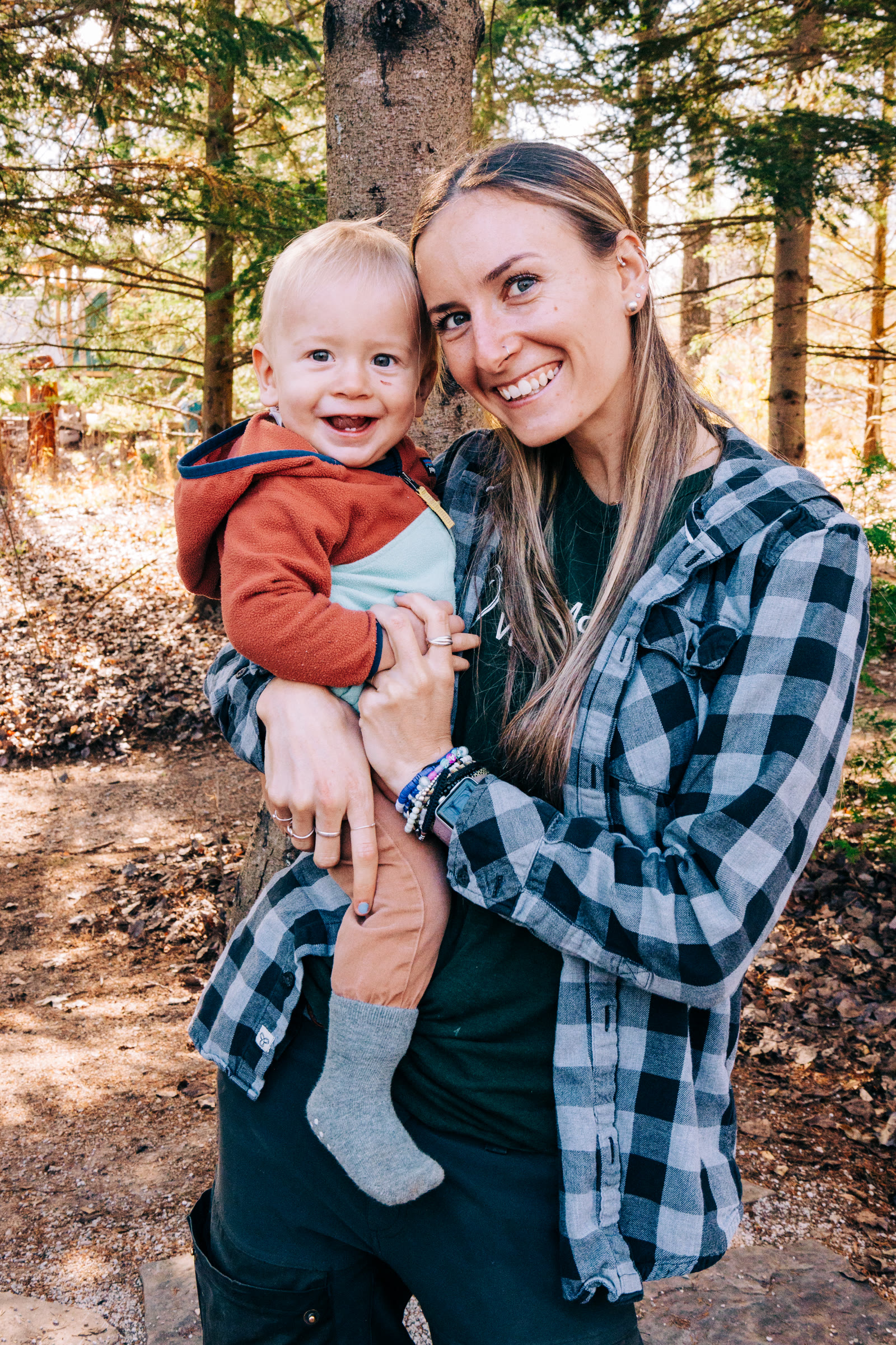 Ali holds a toddler in the woods