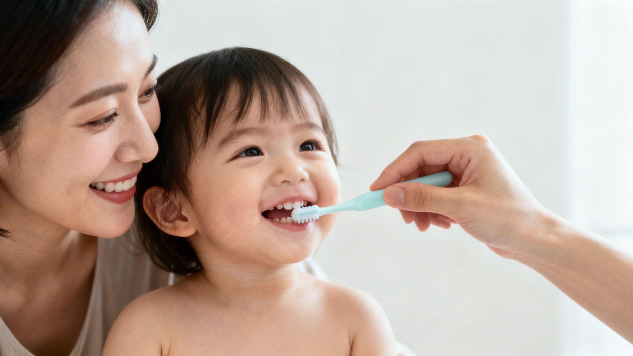 A parent gently brushes their smiling toddler's teeth, promoting good oral hygiene.