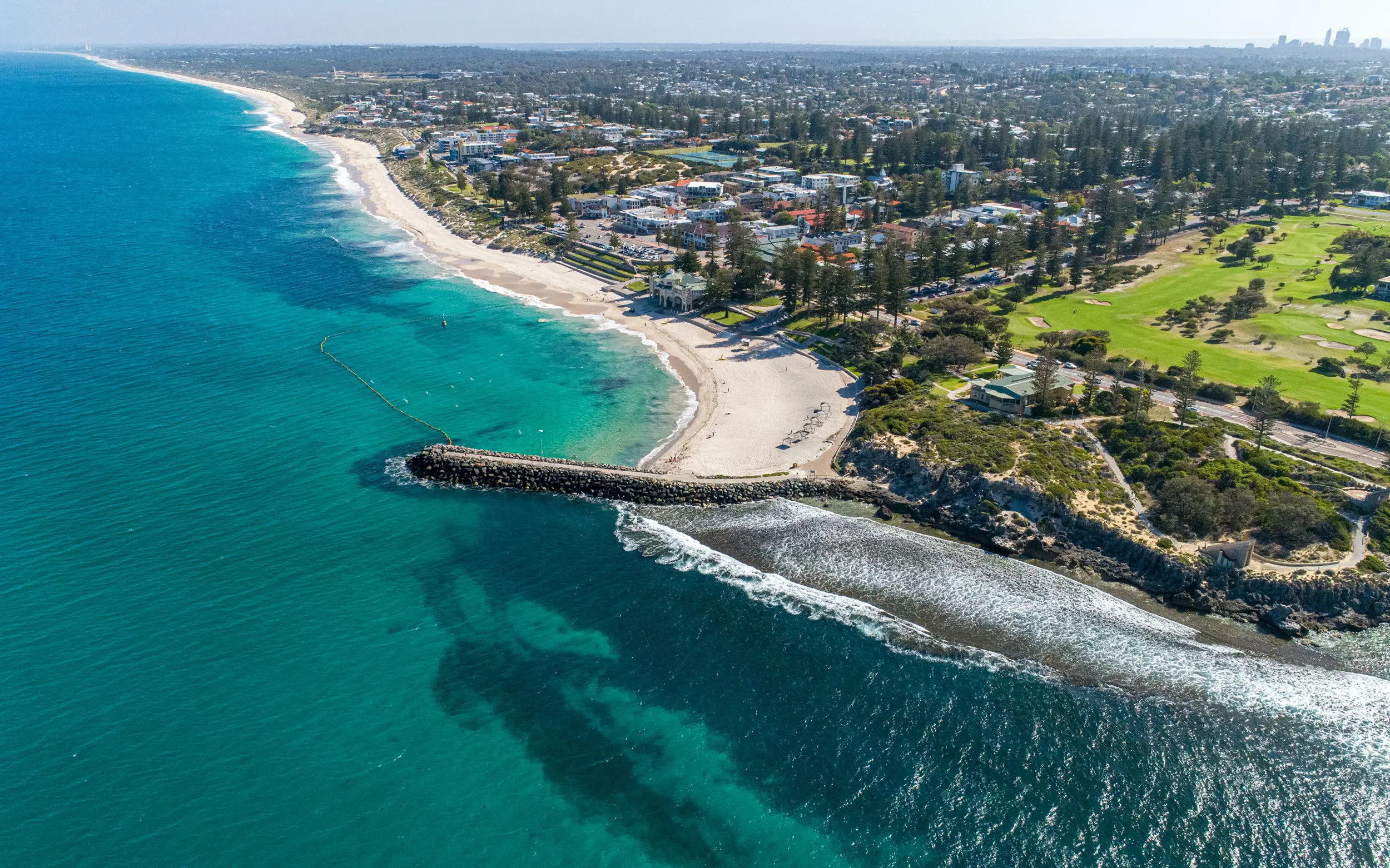 Aerial view of deep turquoise ocean waves with white foam breaking on the surface.