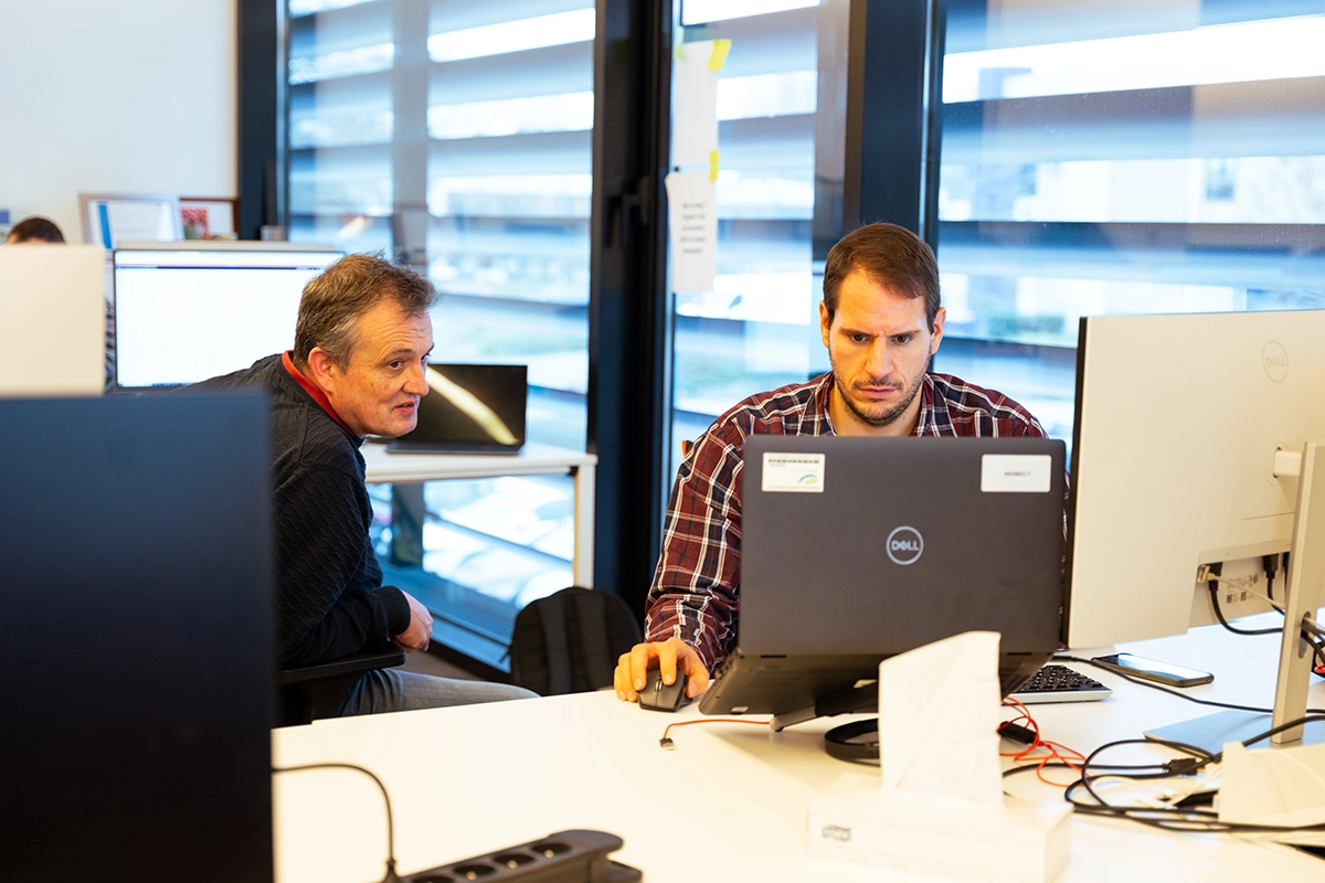 2 men working in an office behind the PC