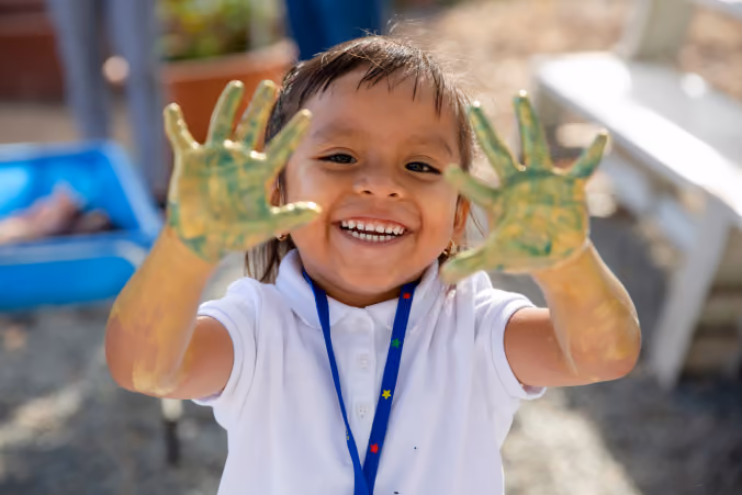 A little girl holding her hands up in the air.