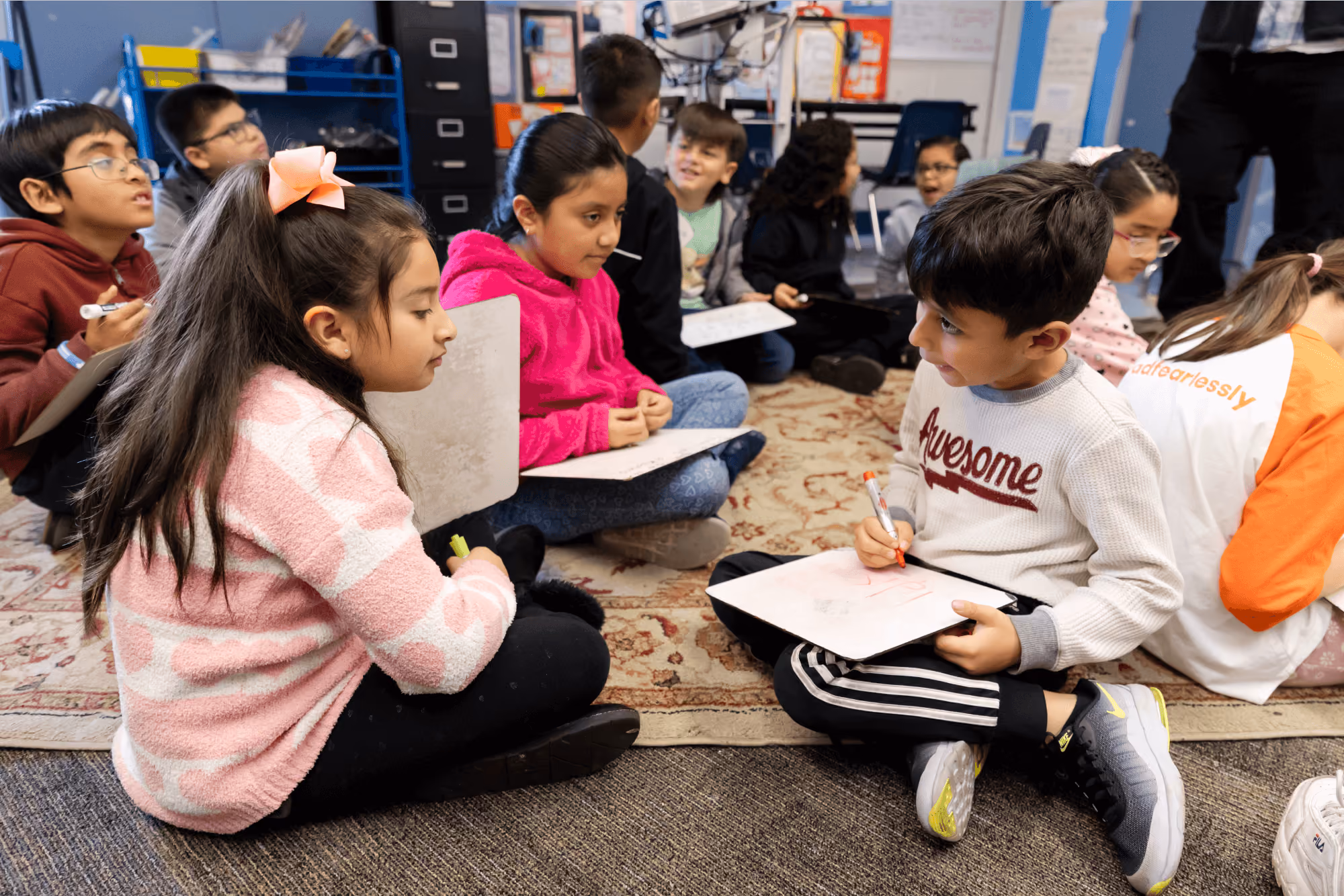A group of children sitting on the floor in a classroom.