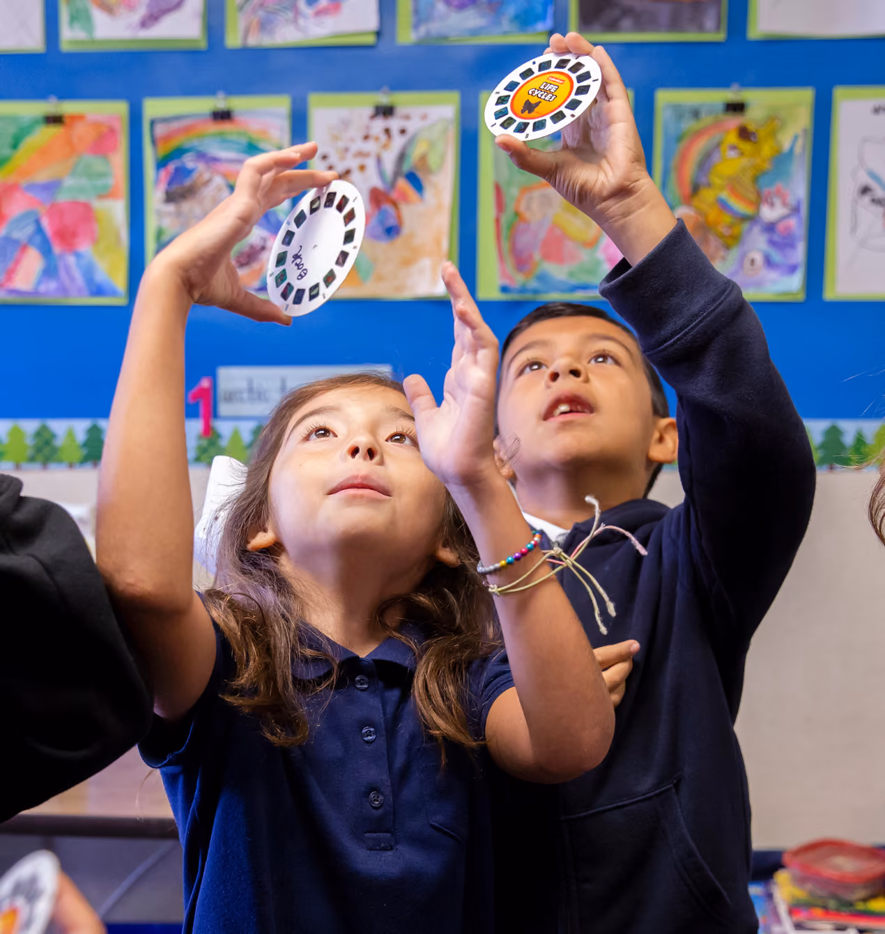Two children holding viewfinder discs, looking in awe.