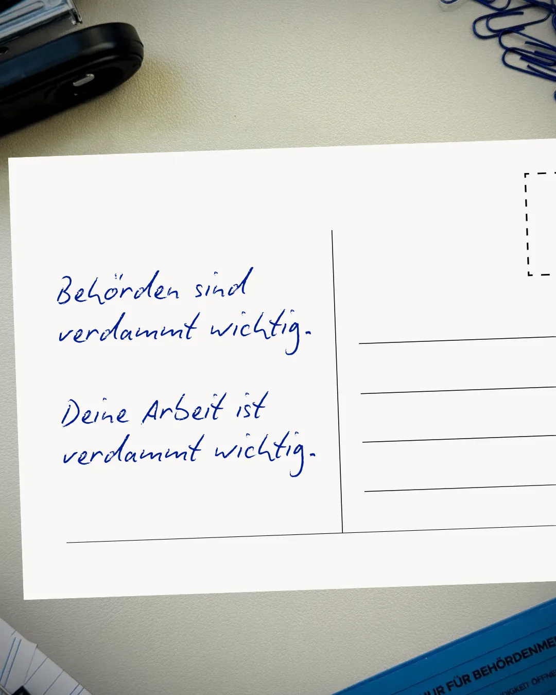 Postkarte mit handgeschriebener Notiz in blauer Tinte: 'Behörden sind verdammt wichtig. Deine Arbeit ist verdammt wichtig.'