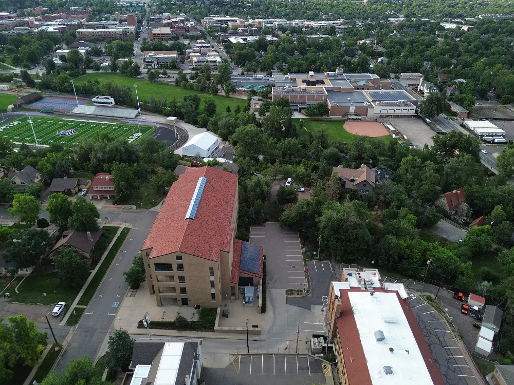 Aerial view of a school campus with sports field, baseball diamond, and surrounding residential area.