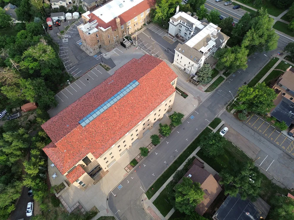 Aerial view of a red-roofed building surrounded by parking lots, streets, and greenery.