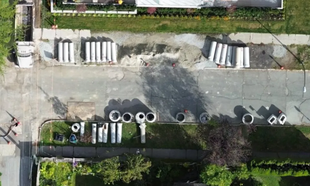 Aerial view of water pipe construction materials laid out along a residential street.