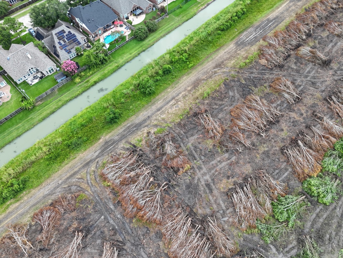 Aerial view of a residential neighborhood with a house under construction surrounded by completed houses and autumn-colored trees.
