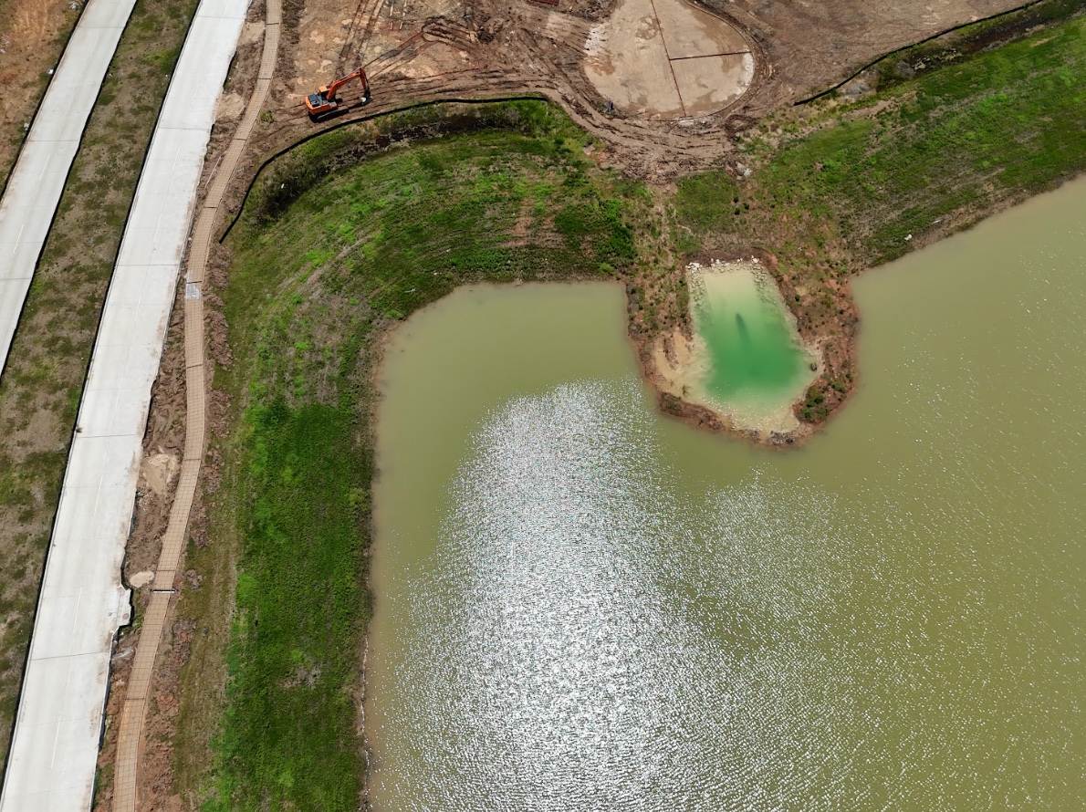 Aerial view of a construction site with steel rebar, wooden planks, pipes, and concrete foundations in progress.
