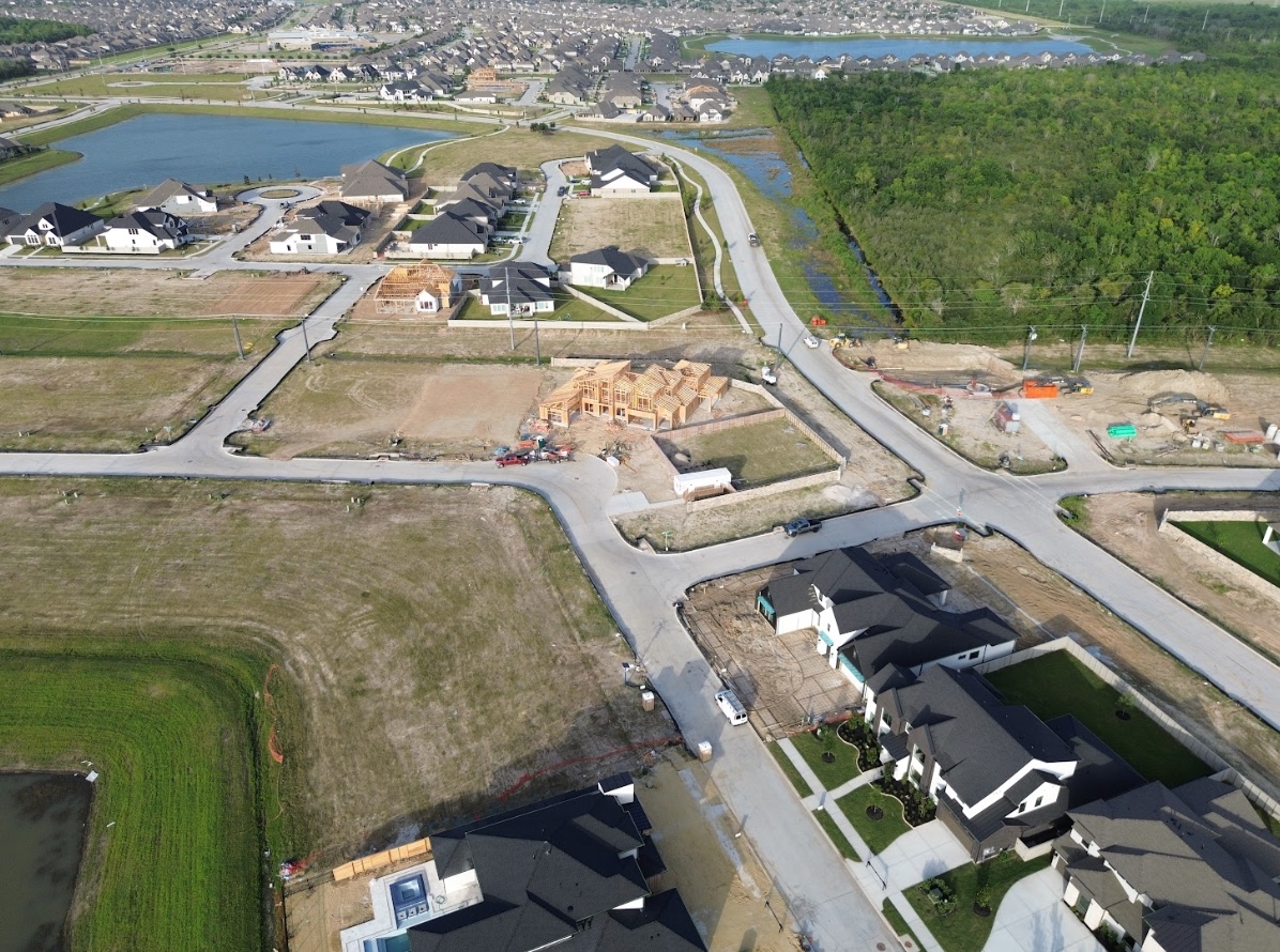 Aerial view of a construction site with steel rebar, wooden planks, pipes, and concrete foundations in progress.