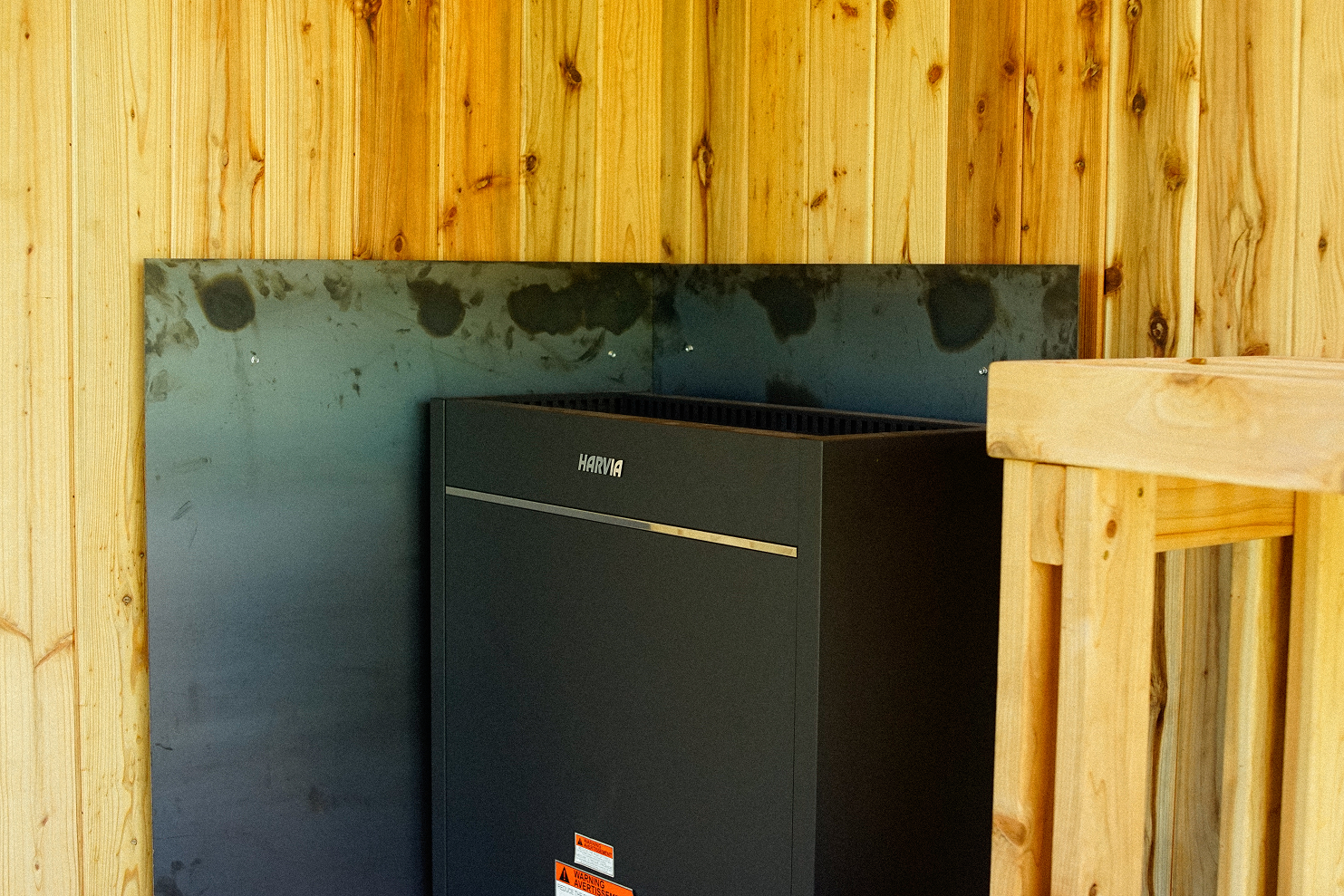 Electric sauna heater beside cedar benches in a Woods & Water container sauna