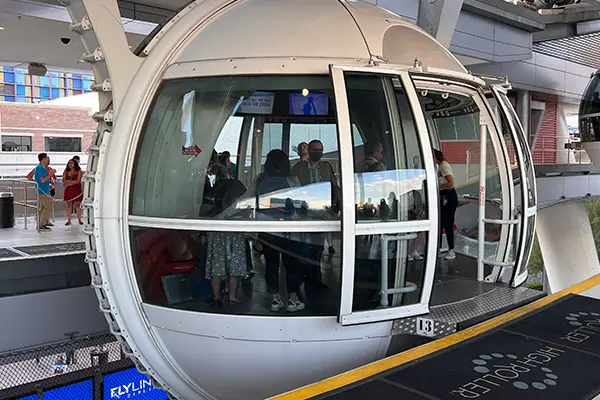 A group of people stand inside a cabin of the High Roller ferris wheel.