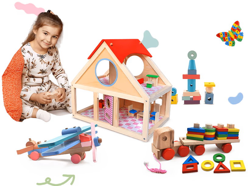 Smiling toddler girl with light brown hair sitting near wooden toys including a dollhouse, airplane, toy train, and colorful stacking blocks.