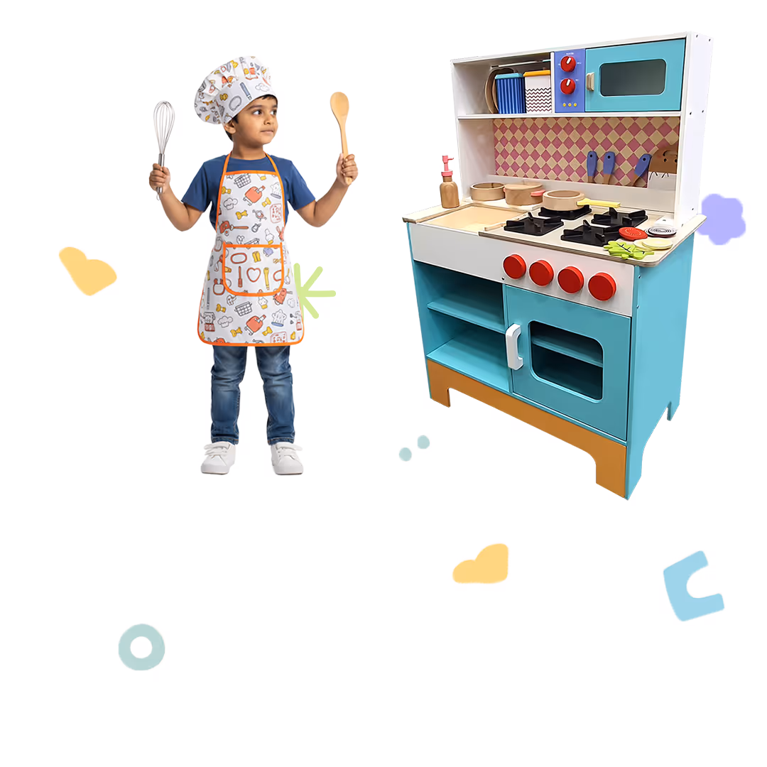 Young child wearing a chef hat and apron, holding a whisk and wooden spoon, standing next to a blue and white toy kitchen set.