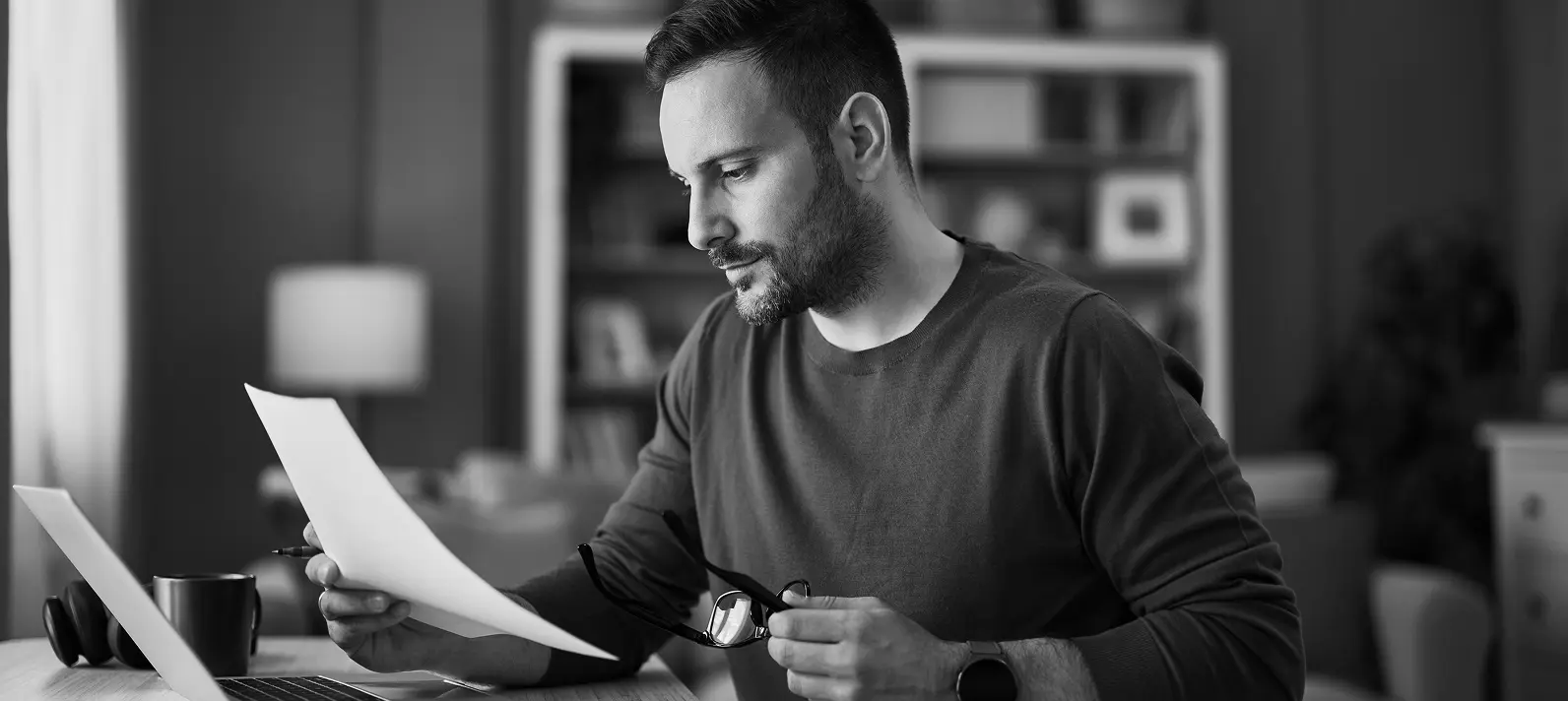 Man reviewing papers in front of laptop