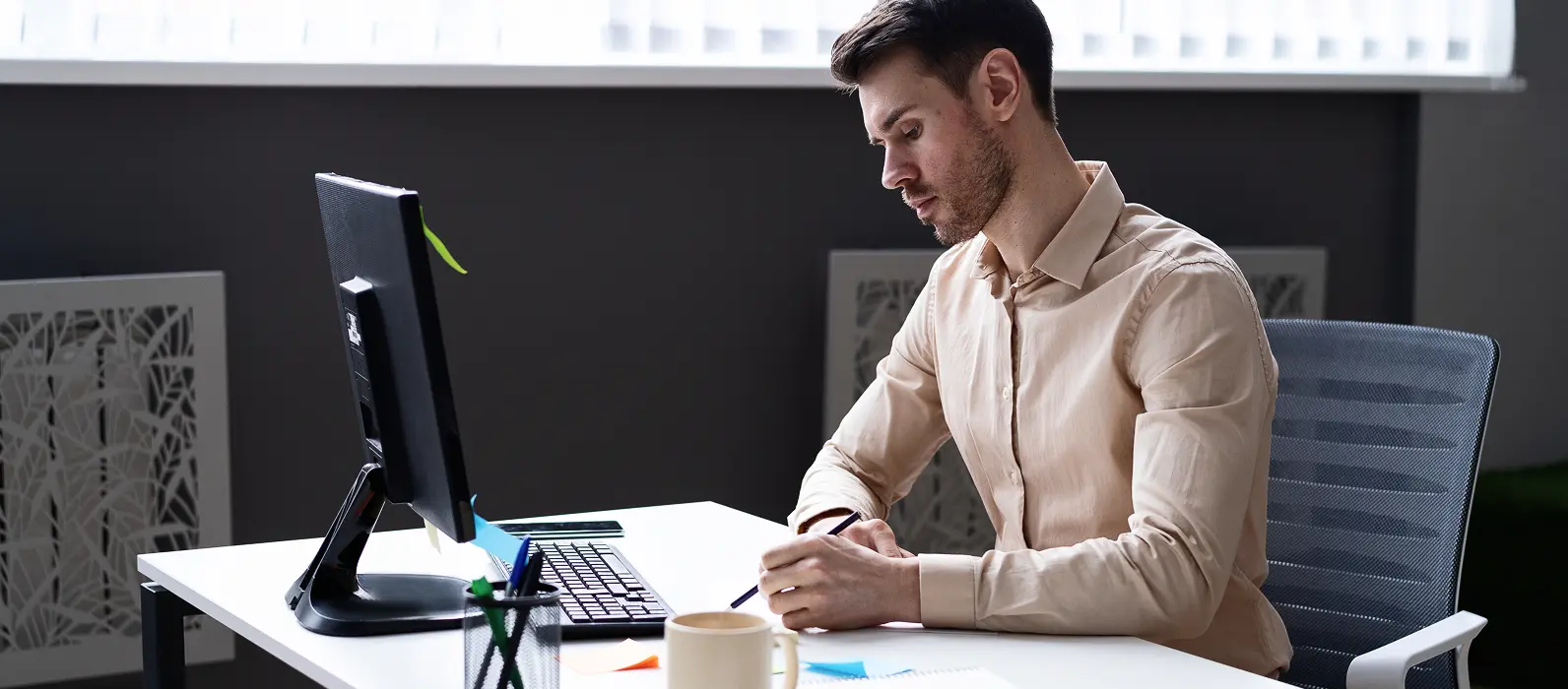 Man writing down information while at computer