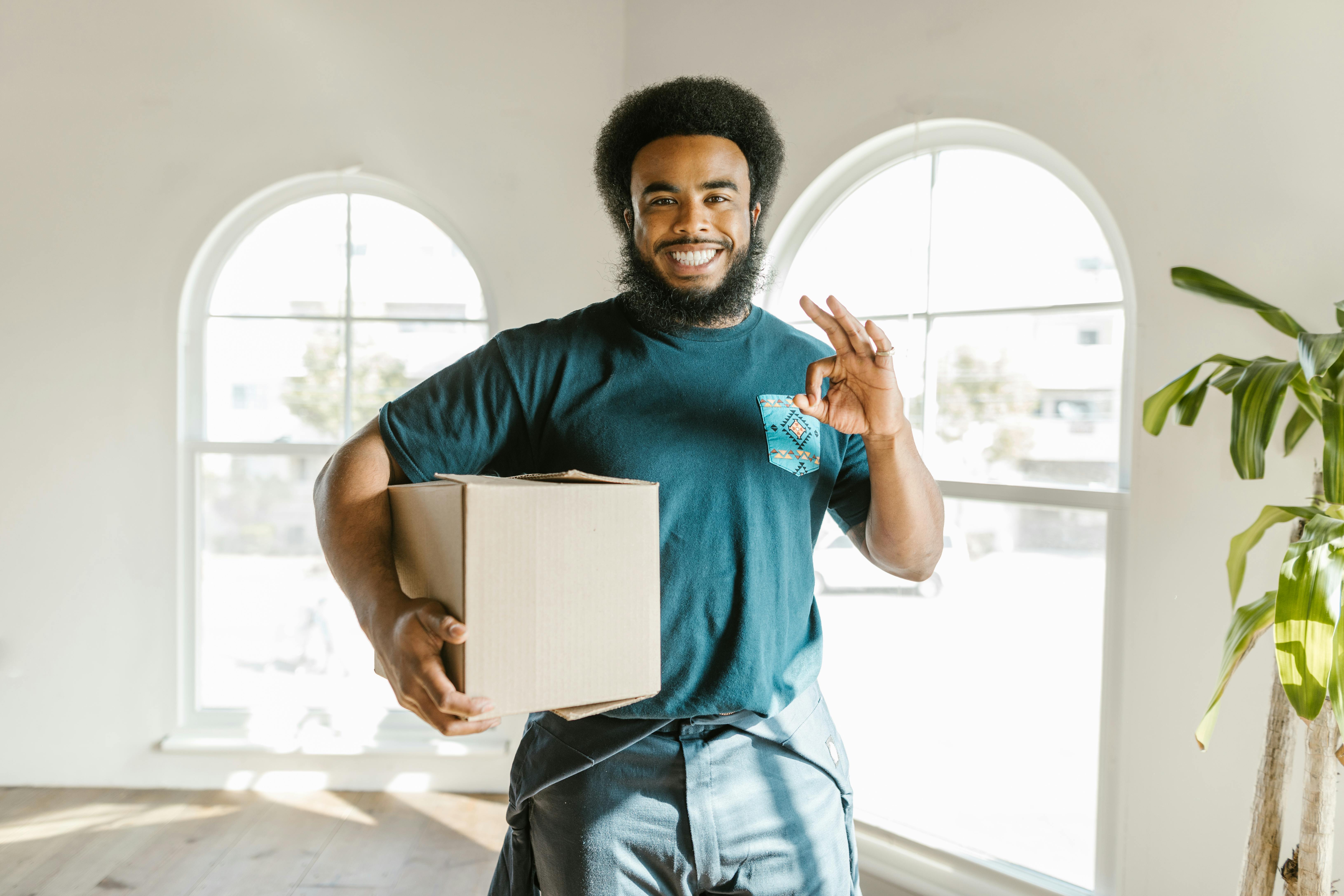 Professional mover holding a box giving an okay sign