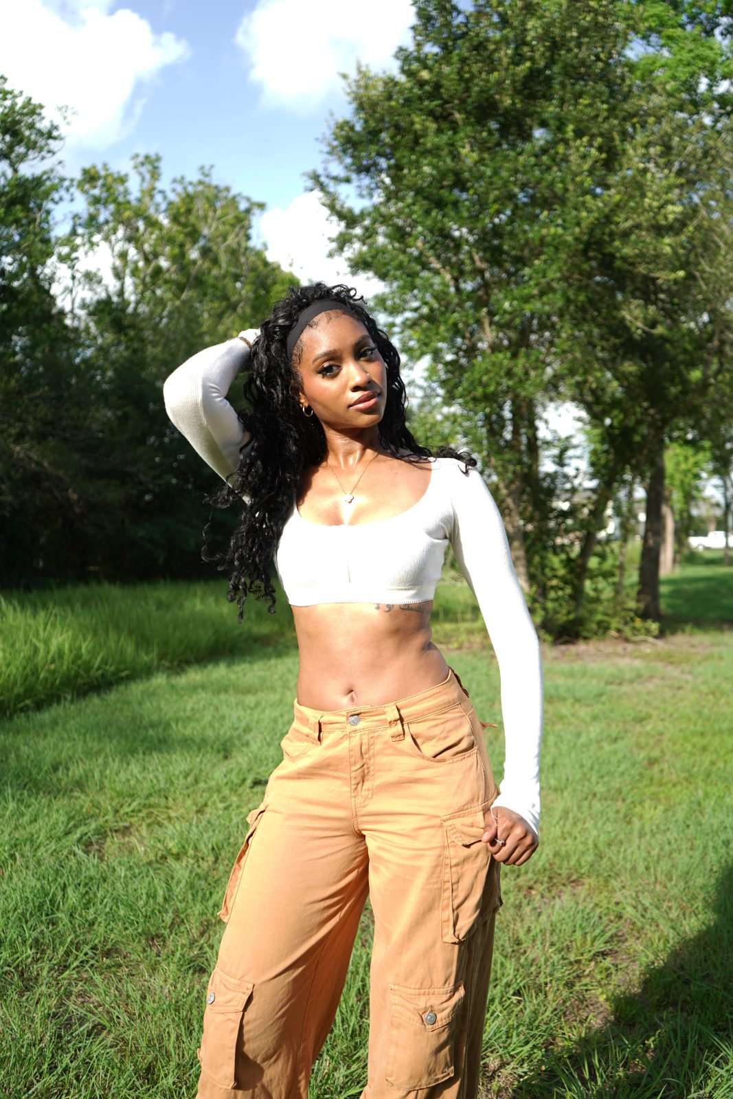 Outdoor fashion portrait in tall grass, white knit and tan cargo trousers