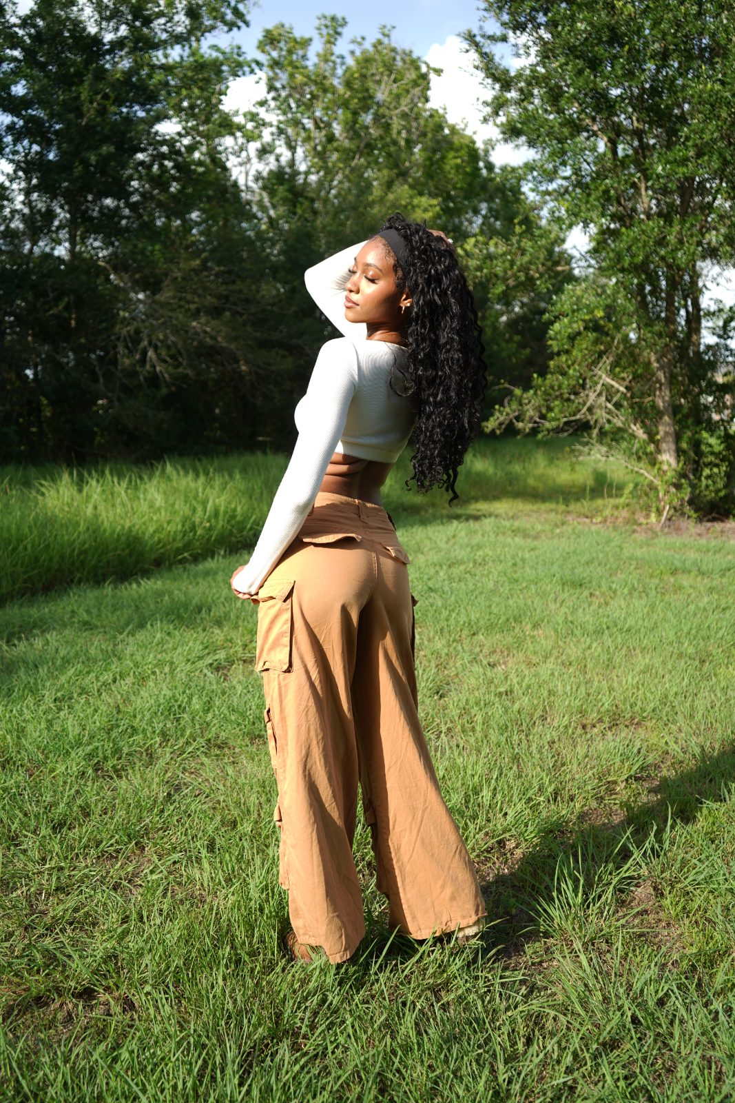 Outdoor fashion portrait in tall grass, white knit and tan cargo trousers