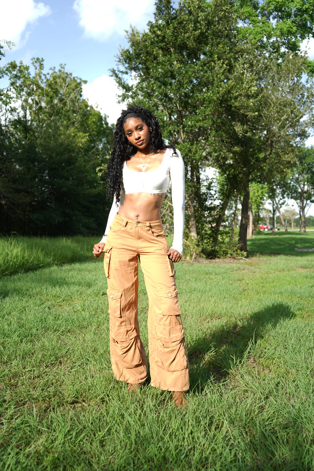 Outdoor fashion portrait in tall grass, white knit and tan cargo trousers