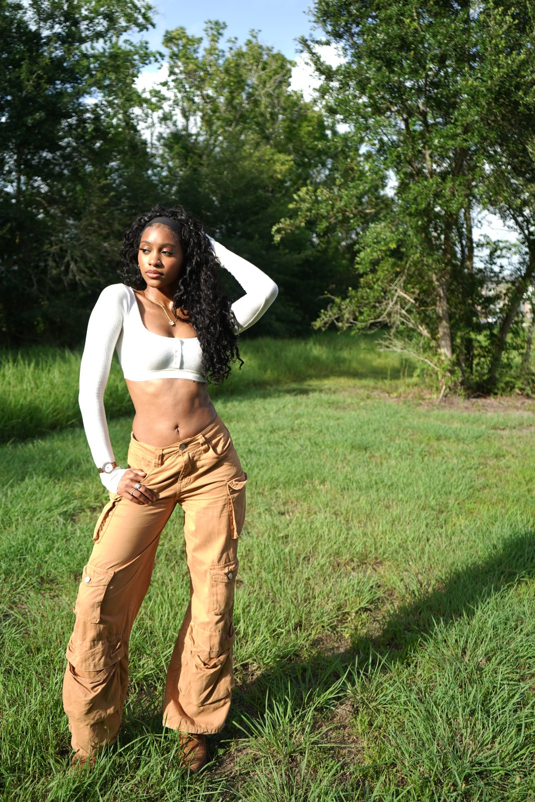 Outdoor fashion portrait in tall grass, white knit and tan cargo trousers