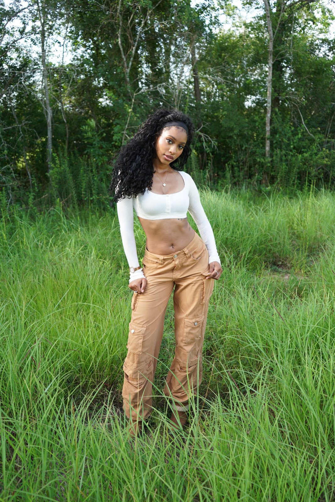 Outdoor fashion portrait in tall grass, white knit and tan cargo trousers