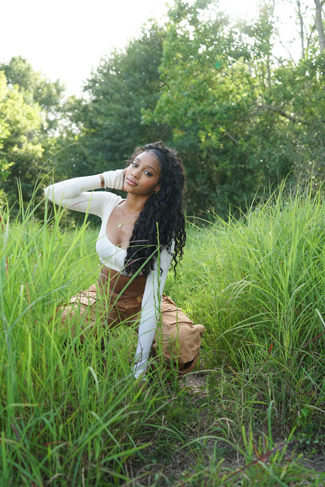 Outdoor fashion portrait in tall grass, white knit and tan cargo trousers