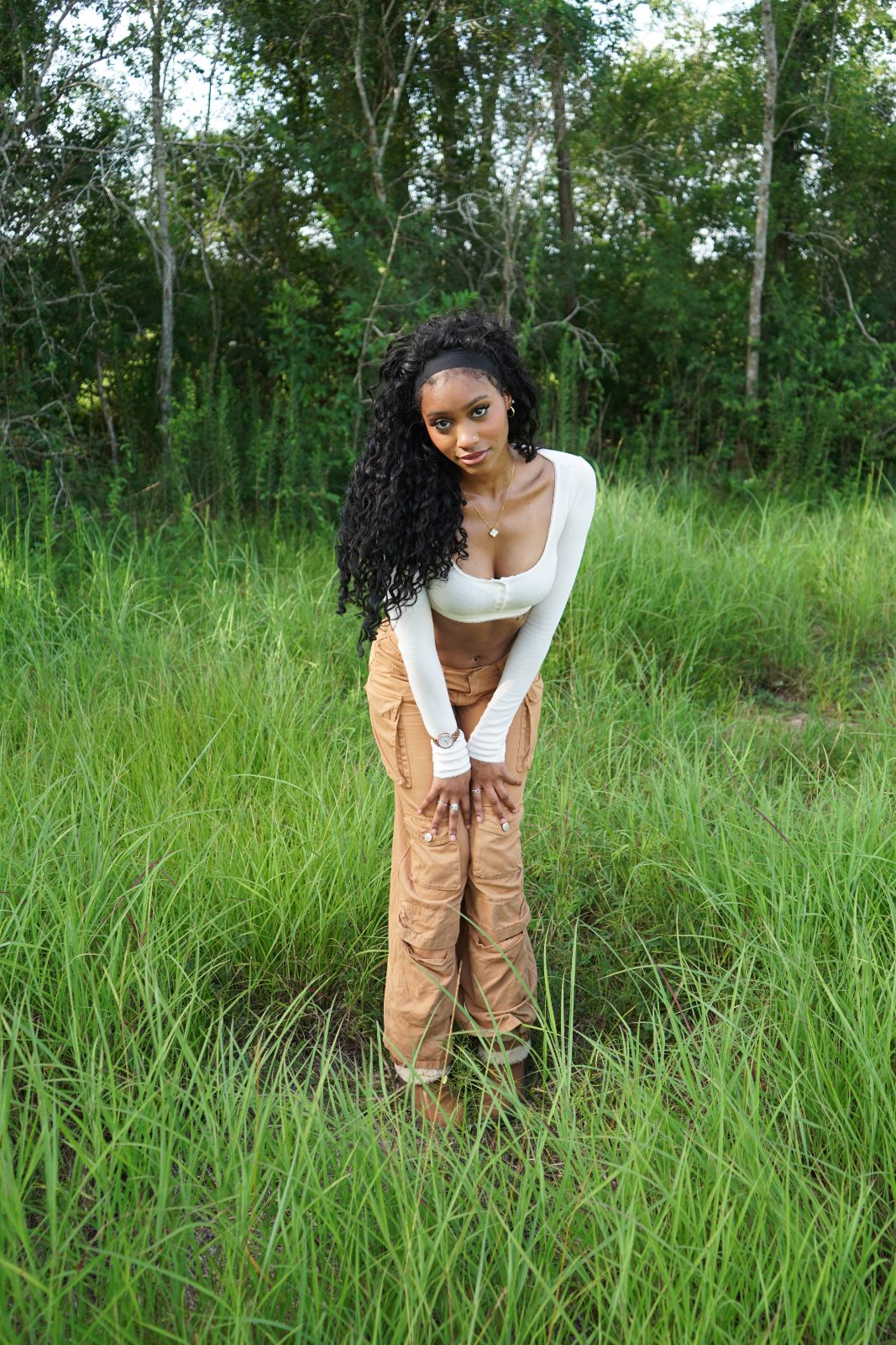 Outdoor fashion portrait in tall grass, white knit and tan cargo trousers